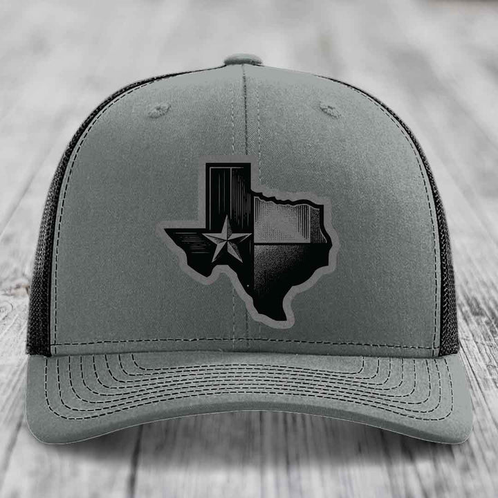 Grey trucker hat with black Texas-shaped patch featuring a star and flag design.