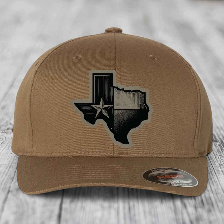 Tan baseball cap with black Texas-shaped patch featuring a star and wood grain design.