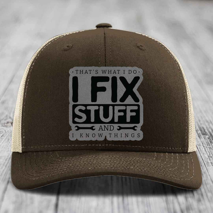 Brown trucker hat with beige mesh back and gray patch reading &