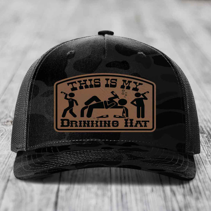 Black camouflage trucker hat with a tan leatherette patch reading &