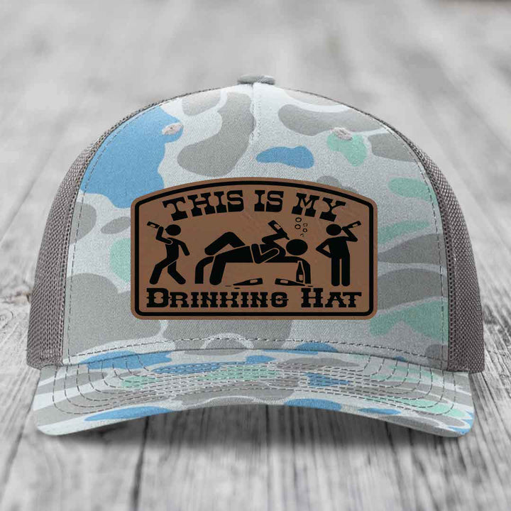 Camouflage trucker hat with brown leather patch reading &