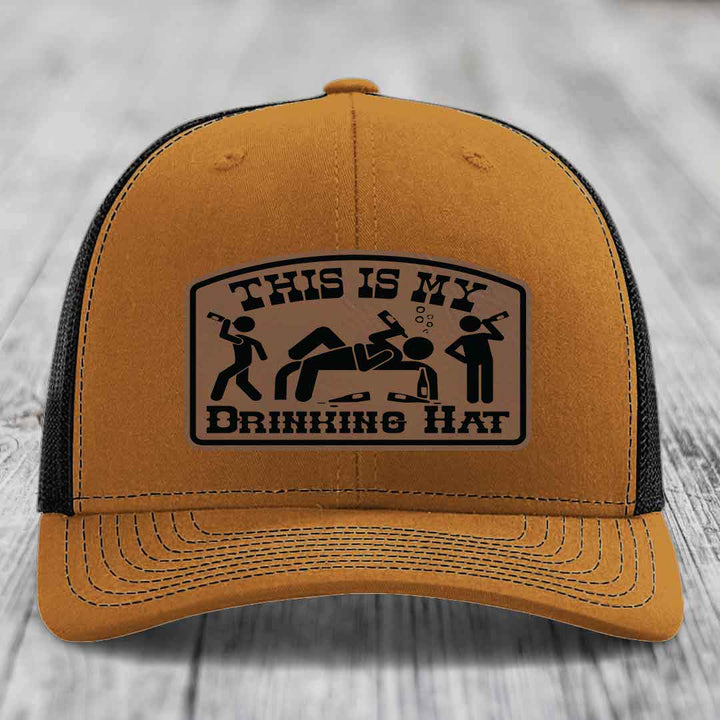 Tan trucker hat with black mesh back and a brown leather patch that reads &