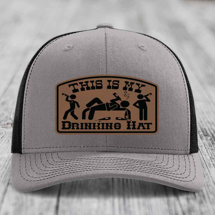 Grey trucker hat with brown leather patch reading &