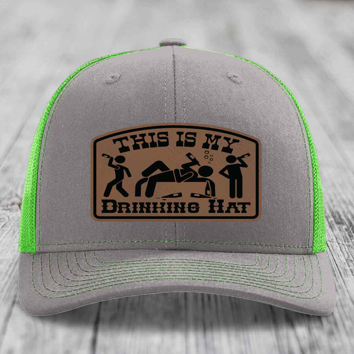 Grey trucker hat with neon green mesh and stitching, featuring a brown leatherette patch that reads &