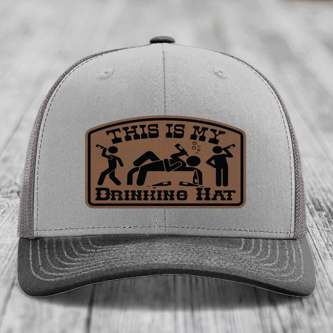 Grey trucker hat with brown leather patch reading &