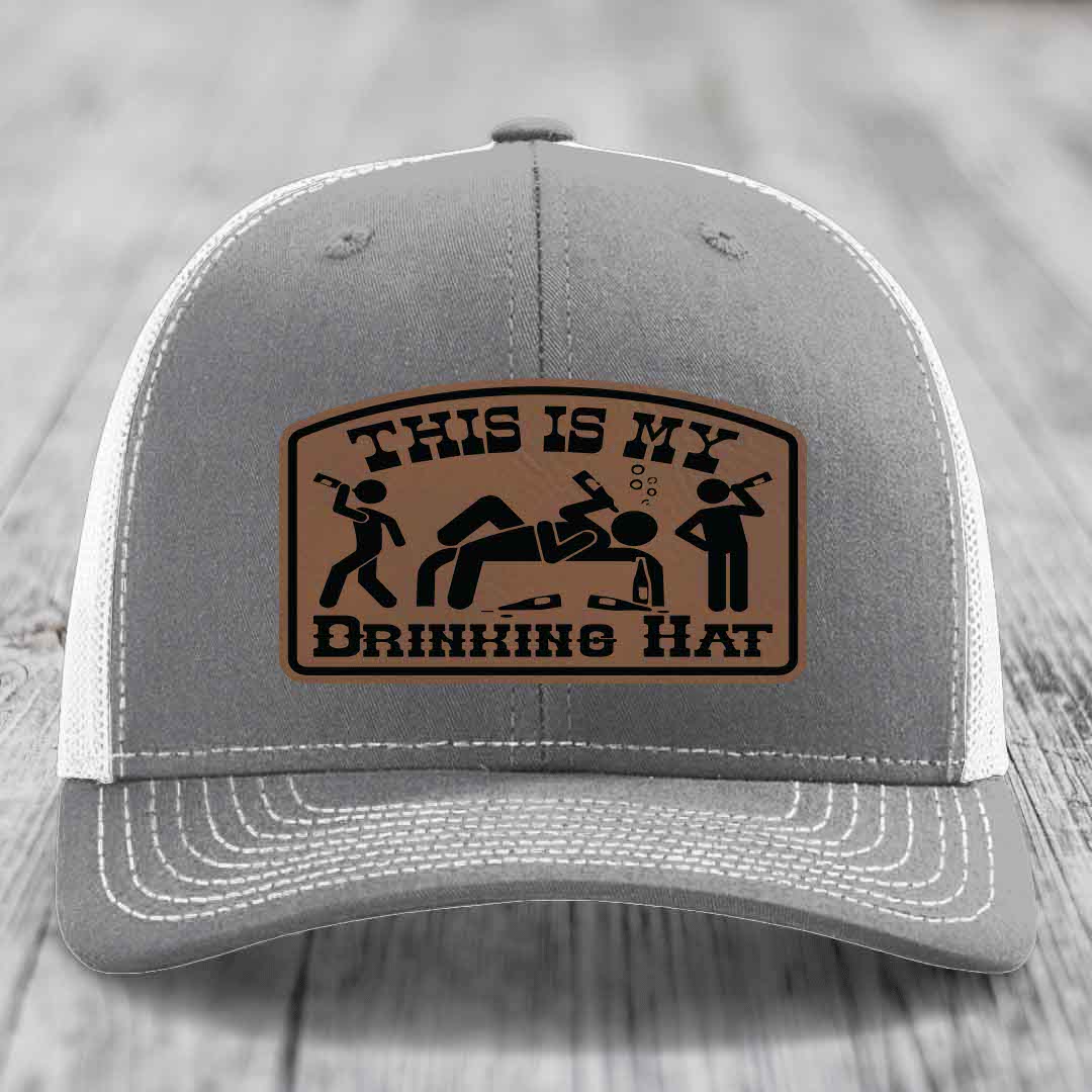 Grey trucker hat with brown leather patch reading &