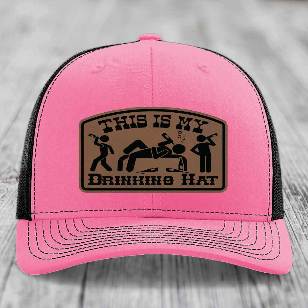Pink trucker hat with black mesh back and a brown leatherette patch reading &