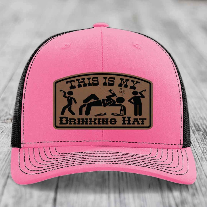 Pink trucker hat with black mesh back and a brown leatherette patch reading &