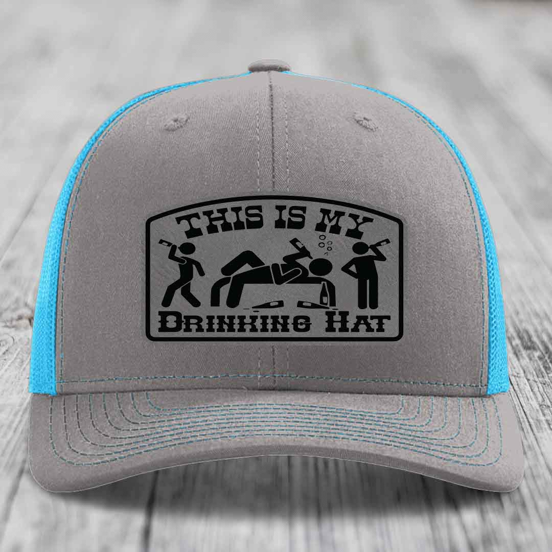 Grey trucker hat with blue mesh back and black patch reading &