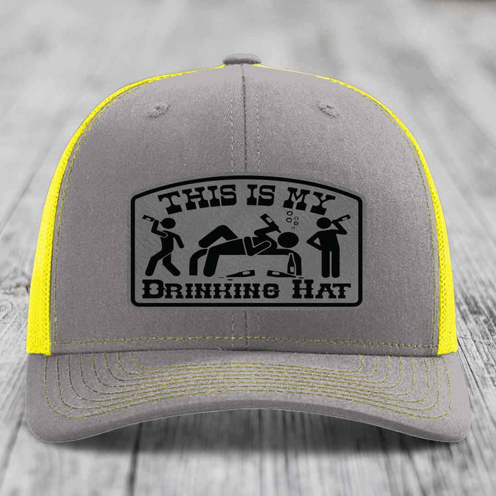 Grey trucker hat with yellow mesh back and black patch reading &