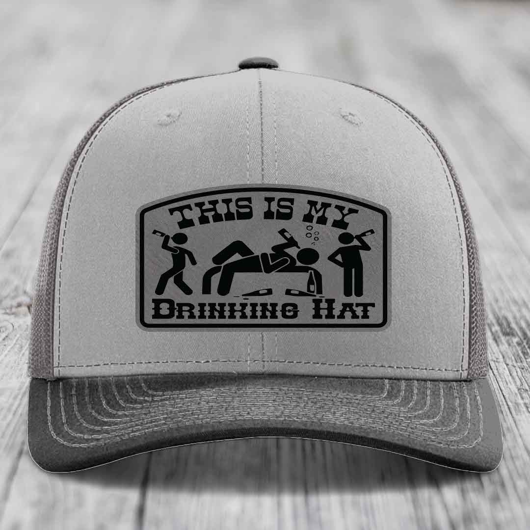Grey trucker hat with black leatherette patch reading &