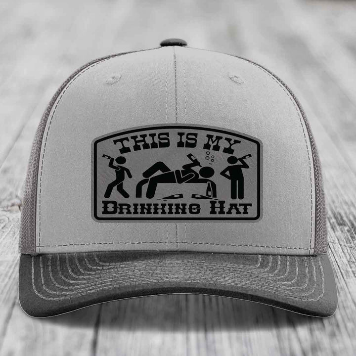 Grey trucker hat with black leatherette patch reading &