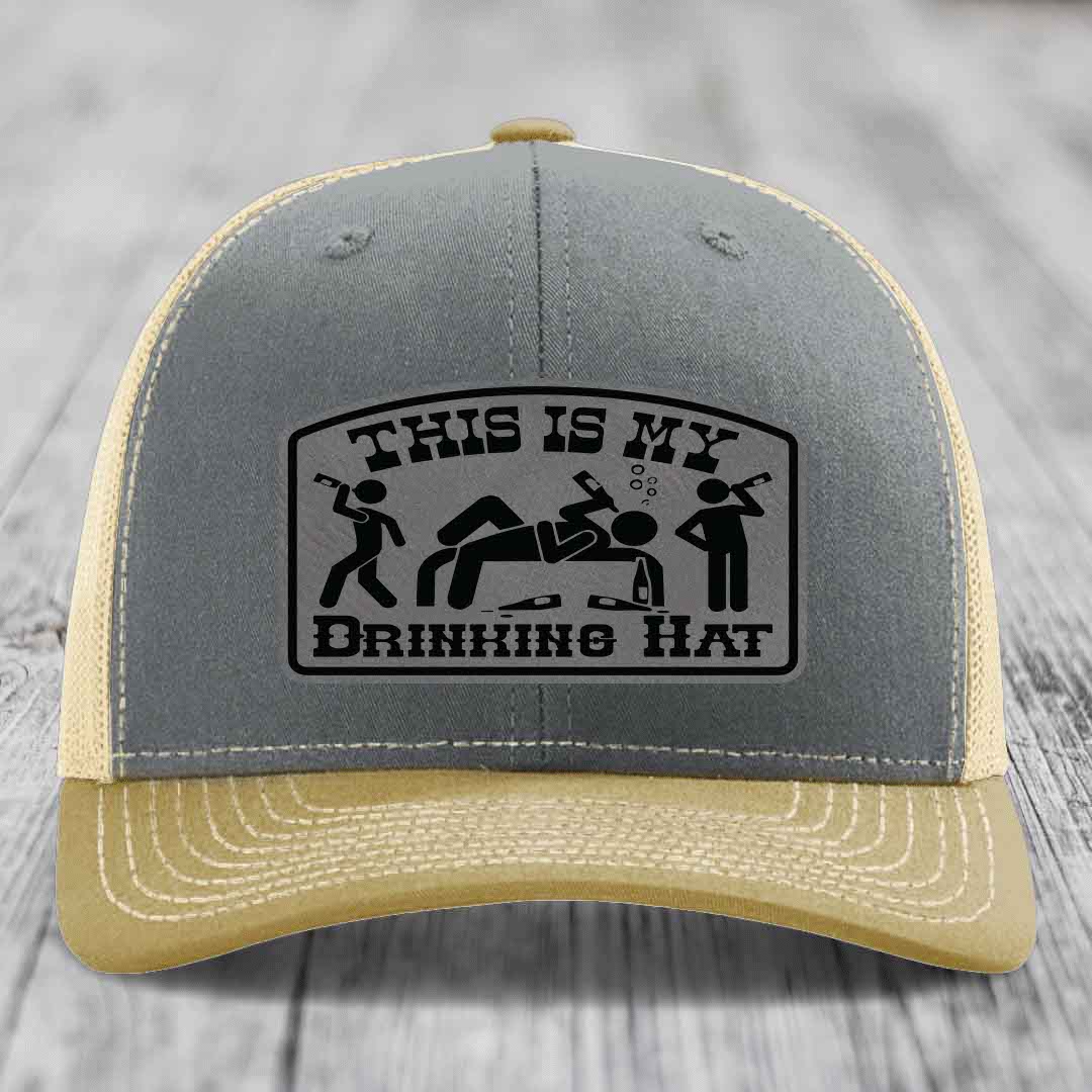 Grey and beige trucker hat with black leatherette patch reading &