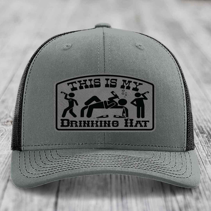 Grey trucker hat with black leatherette patch reading &