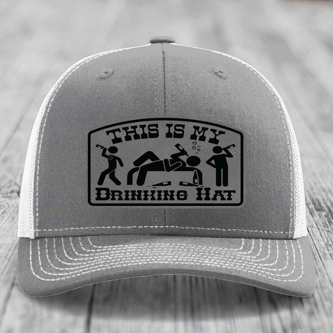 Grey trucker hat with black embroidered patch reading &