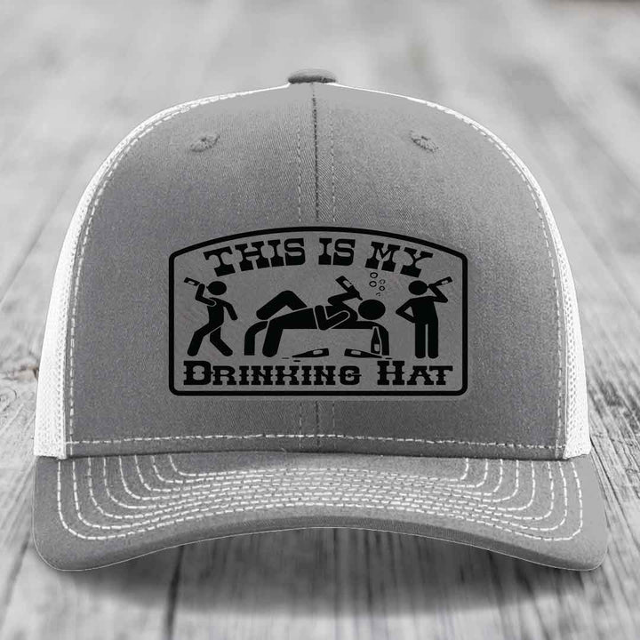Grey trucker hat with black embroidered patch reading &