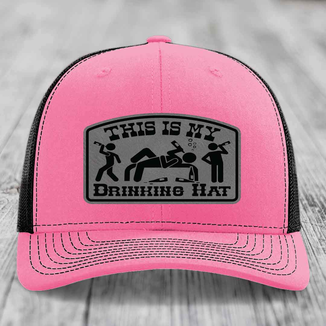 Pink trucker hat with black mesh back and gray leather patch reading &