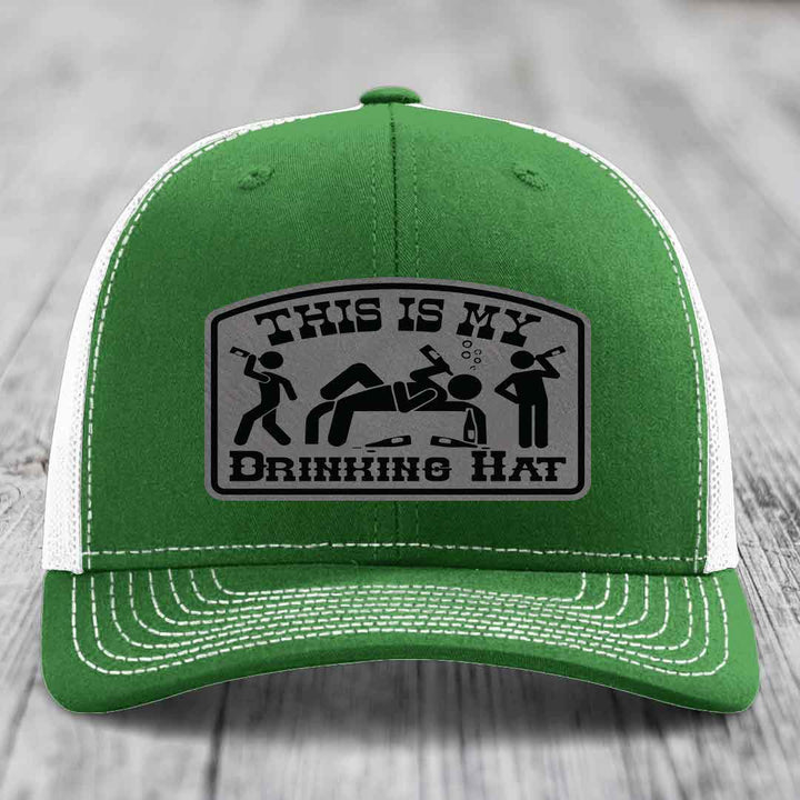 Green trucker hat with white mesh back and stitching, featuring a gray leatherette patch that reads &