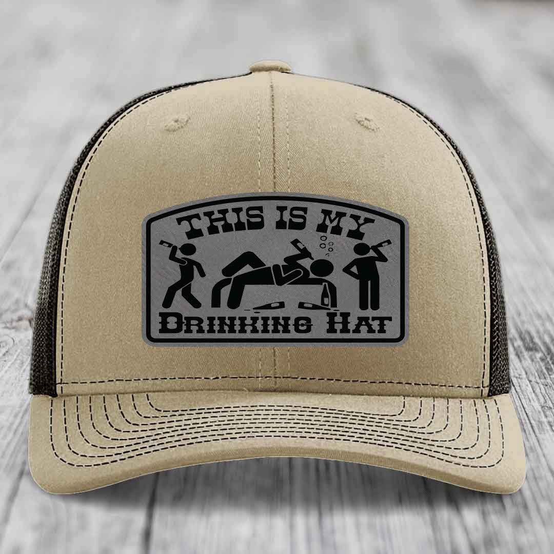 Beige trucker hat with black mesh back and a gray leatherette patch reading &