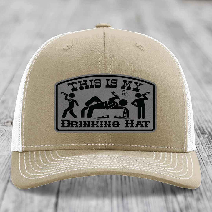 Tan trucker hat with a black and grey leatherette patch that reads &