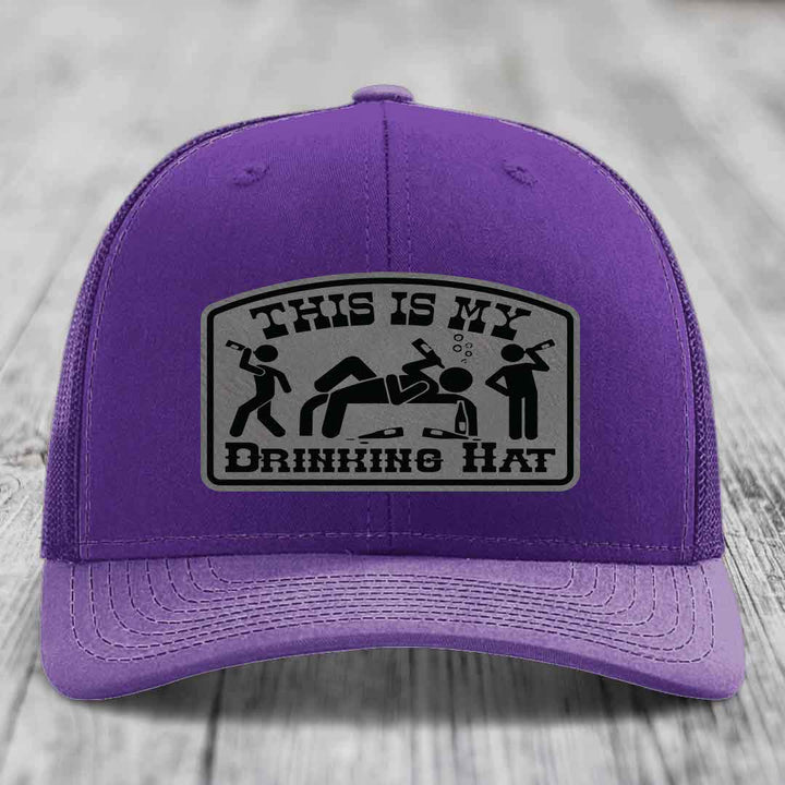 Purple trucker hat with a gray leatherette patch reading &