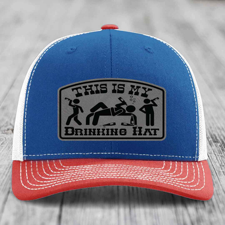 Blue and red trucker hat with a gray leatherette patch that reads &