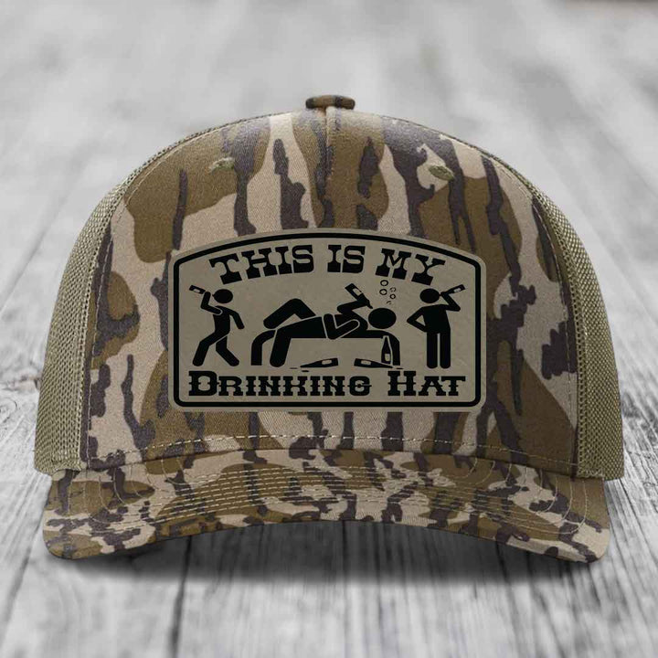 Camouflage trucker hat with a black leatherette patch reading &