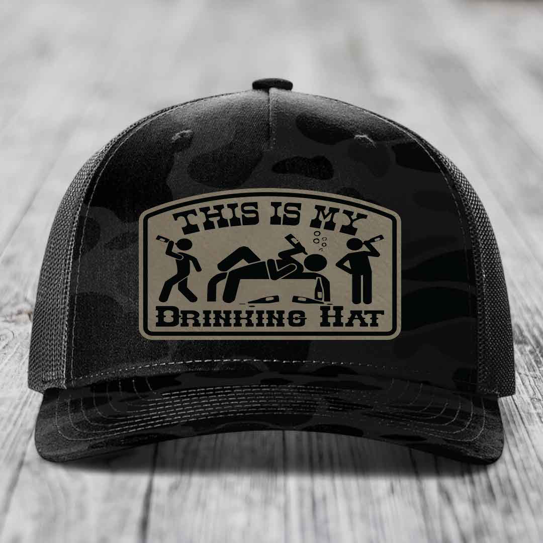 Black camouflage trucker hat with a tan leatherette patch reading &