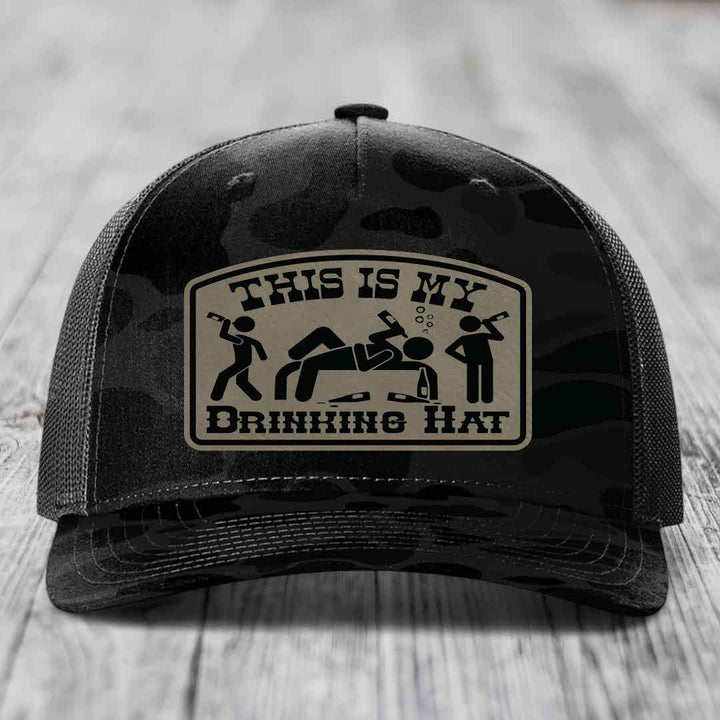 Black camouflage trucker hat with a tan leatherette patch reading &