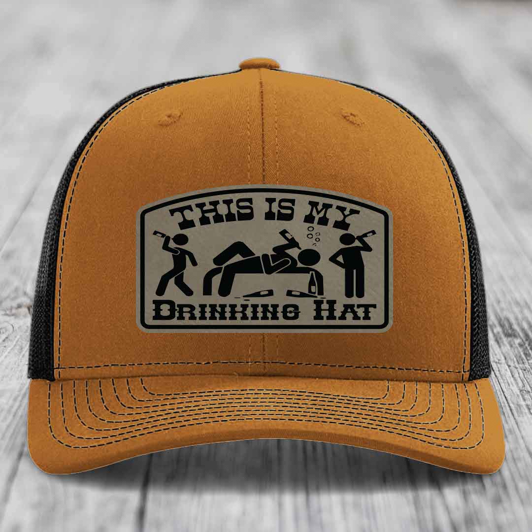 Tan trucker hat with black mesh back and a rectangular leatherette patch reading &