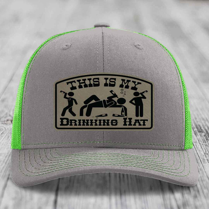 Grey trucker hat with neon green mesh and a black leatherette patch reading &