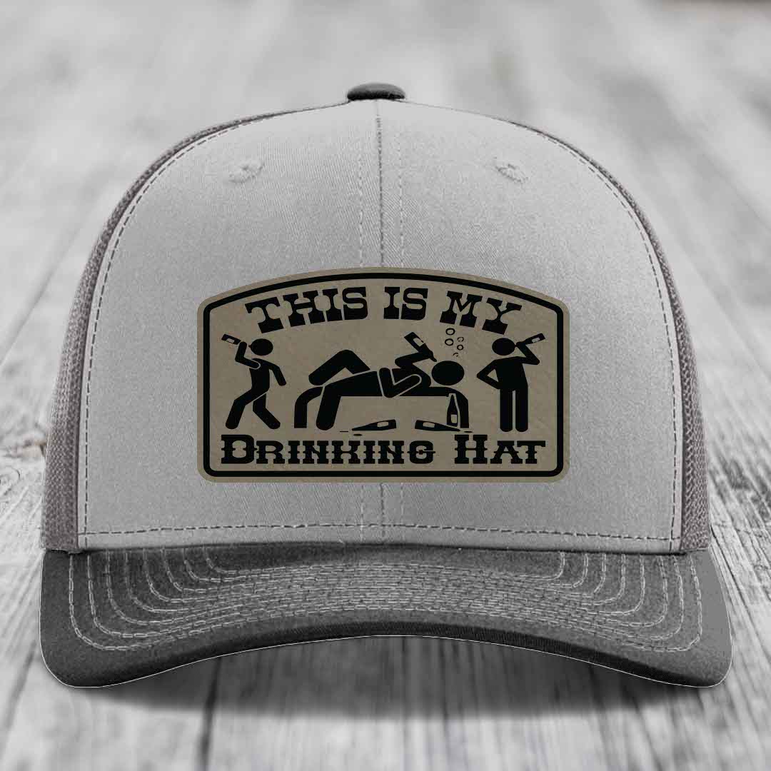 Grey trucker hat with black and tan leather patch reading &