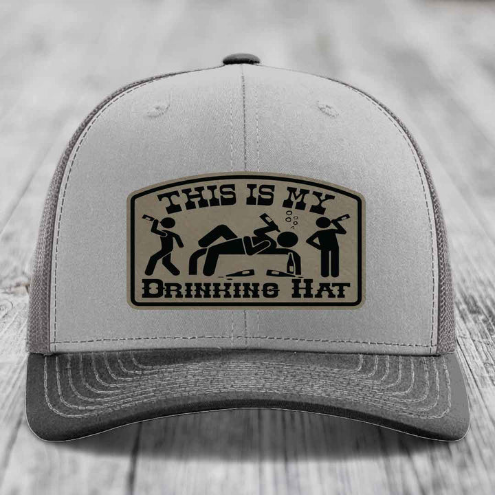 Grey trucker hat with black and tan leather patch reading &