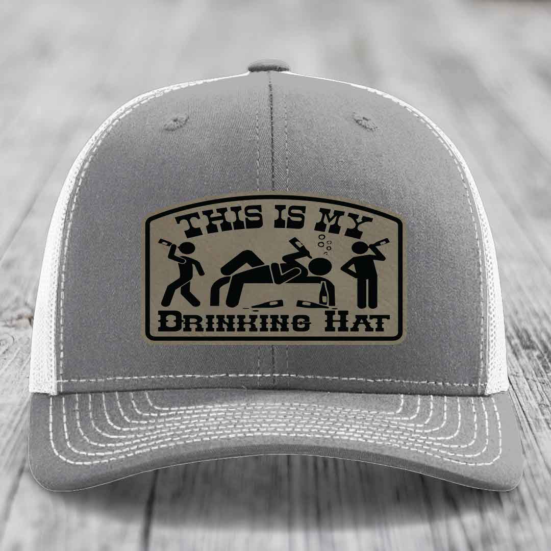 Grey trucker hat with a beige leatherette patch reading &