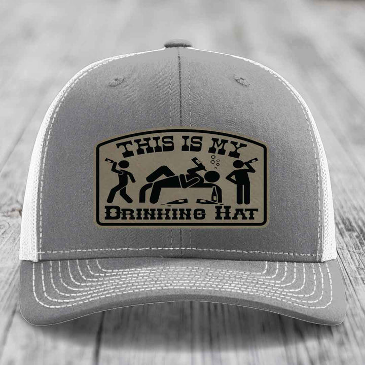 Grey trucker hat with a beige leatherette patch reading &