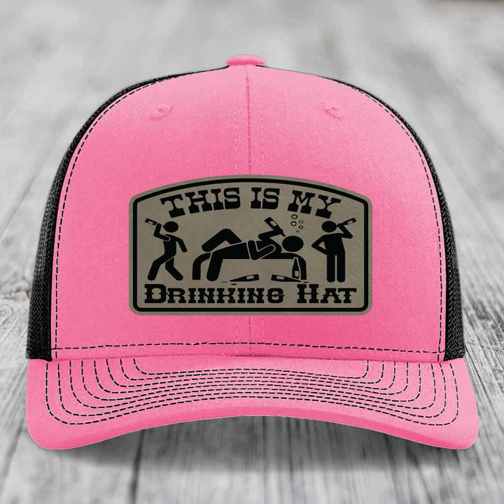 Pink trucker hat with black mesh back and a beige leatherette patch reading &