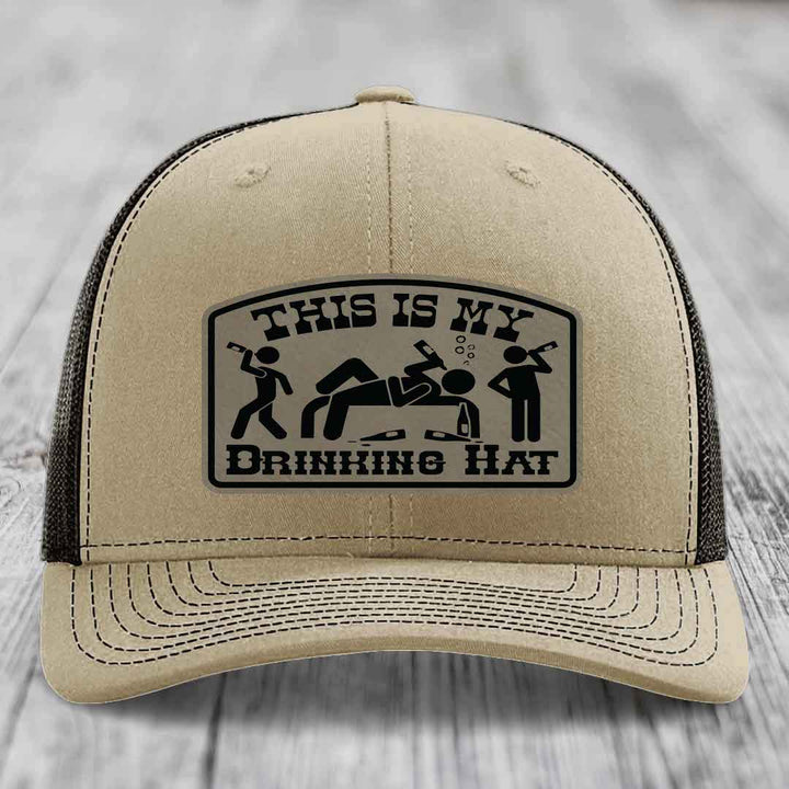 Tan trucker hat with black mesh back and a black leatherette patch reading &