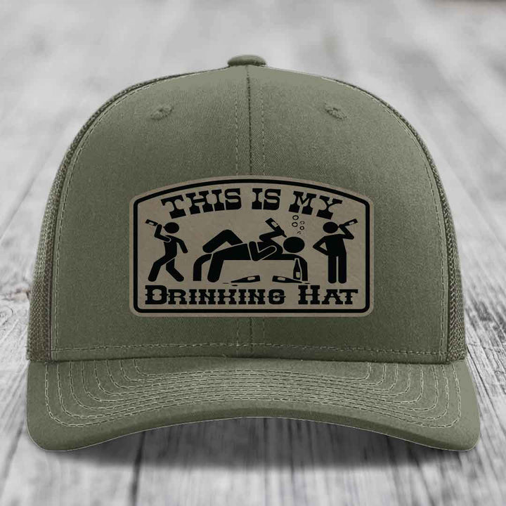 Olive green trucker hat with a beige leather patch that reads &