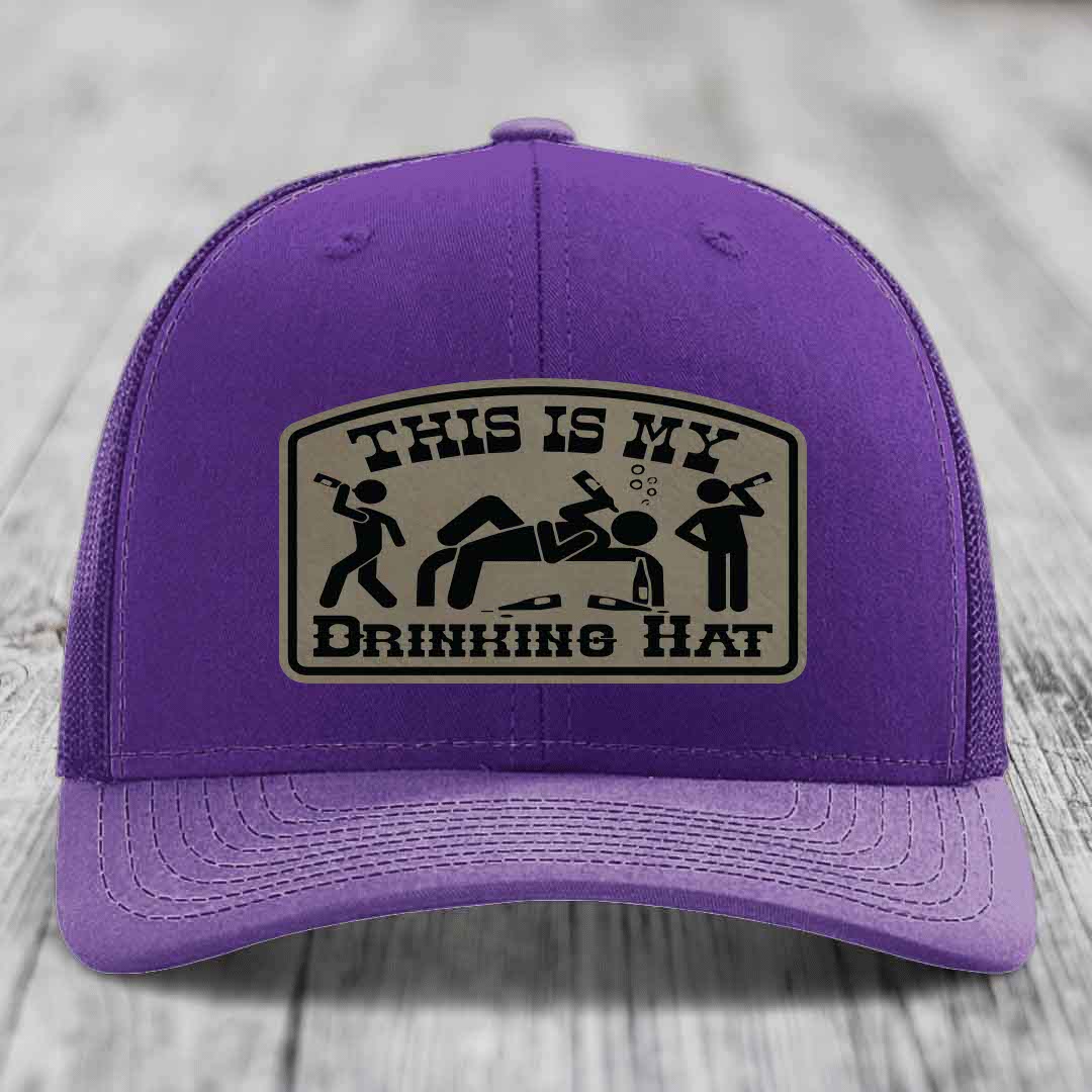 Purple trucker hat with a beige leatherette patch reading &