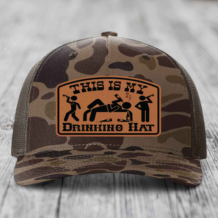 Camouflage trucker hat with brown leather patch reading &