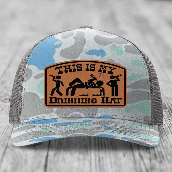 Camouflage trucker hat with brown leather patch reading &