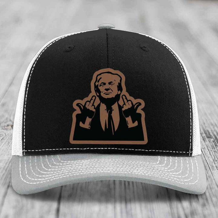 Black and white trucker hat with brown leather patch of man making rude hand gesture.