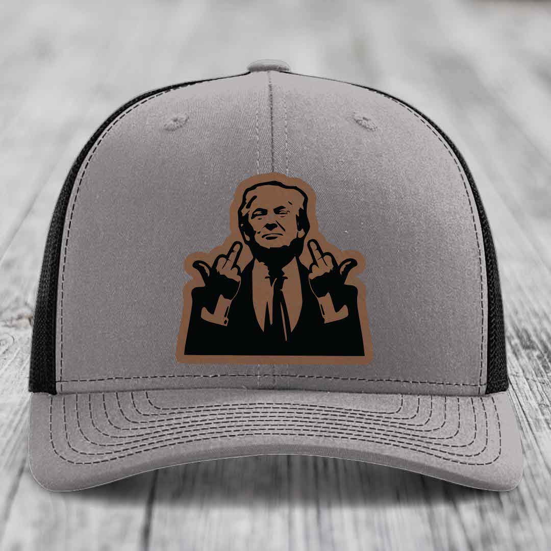 Grey trucker hat with black mesh back and brown leather patch of a man giving two middle fingers.