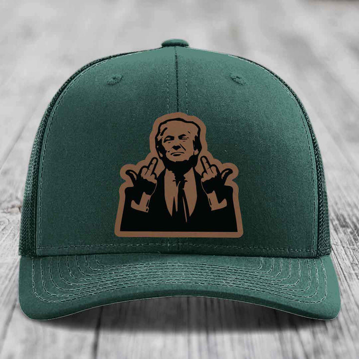 Green trucker hat with a brown and black leatherette patch of a man giving two middle fingers.