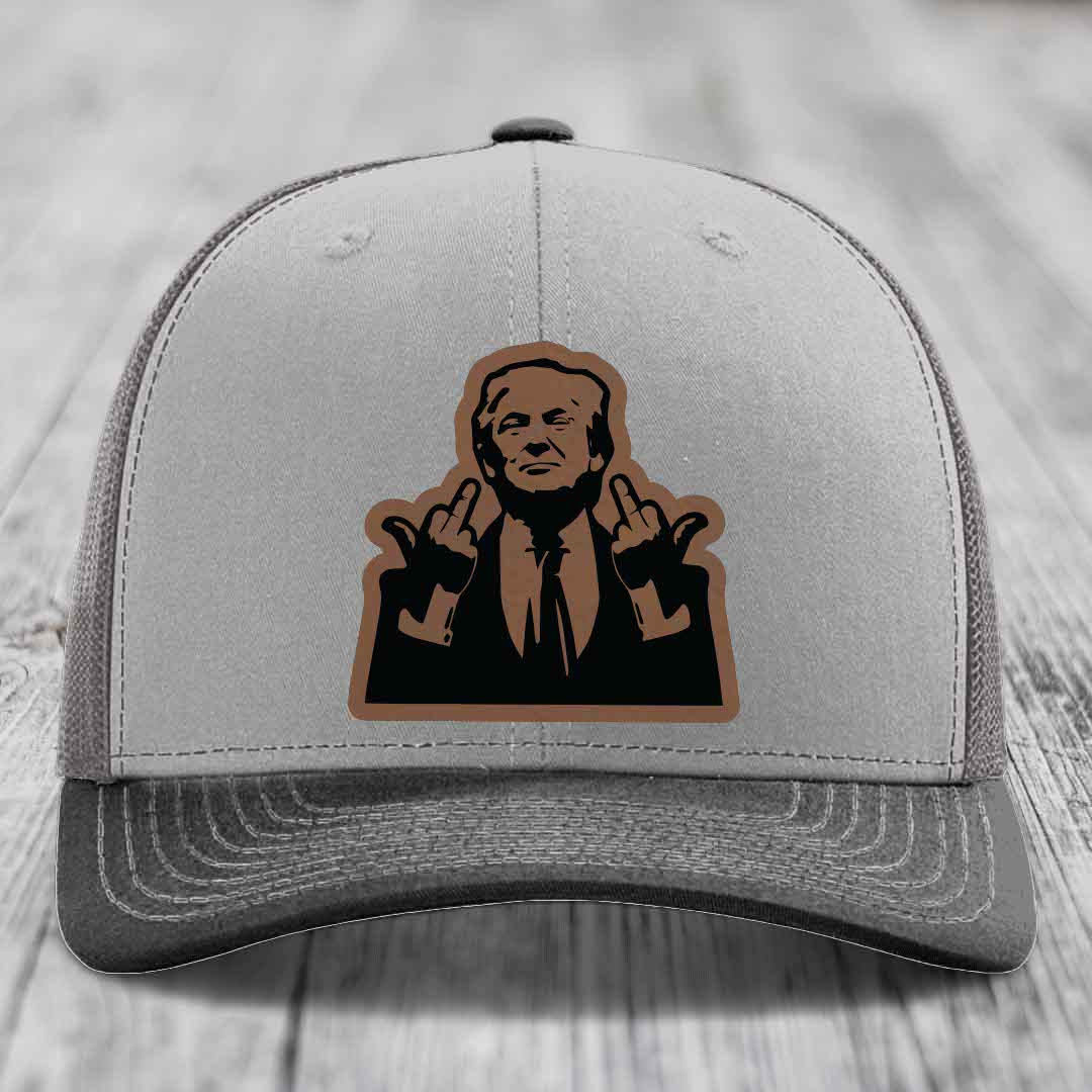 Grey trucker hat with brown and black leather patch of man making rude hand gestures.