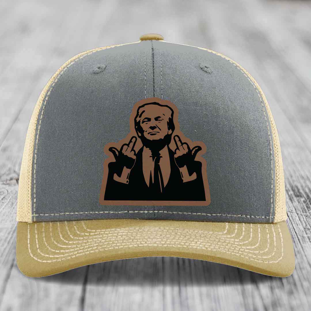 Grey and beige trucker hat with a black leatherette patch of a man making hand gestures.