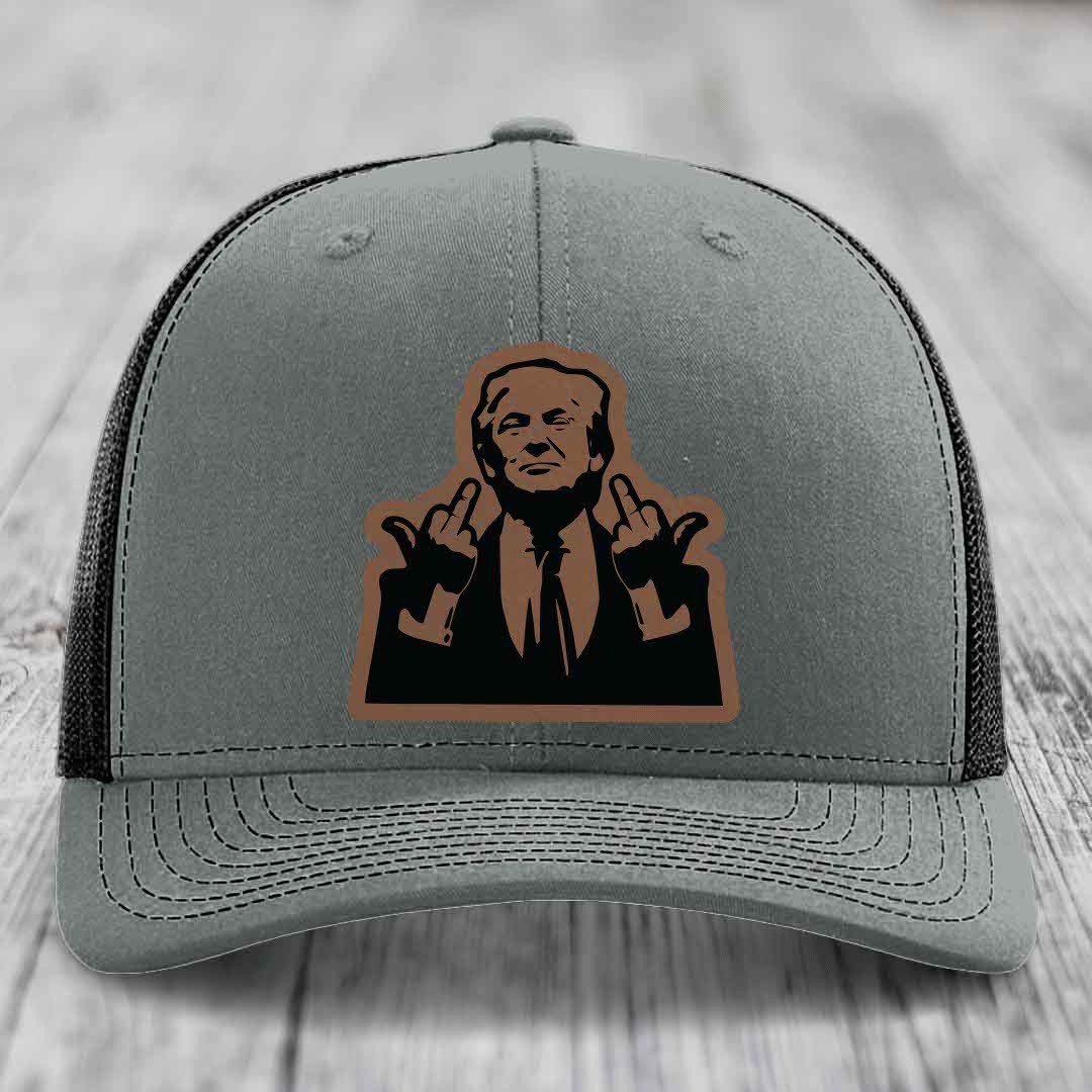 Grey trucker hat with black mesh back and brown leather patch of man giving middle finger
