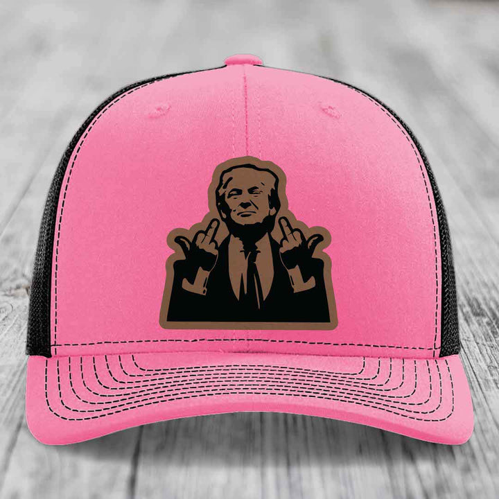 Pink trucker hat with black mesh back and a brown leather patch of a man making rude hand gestures.