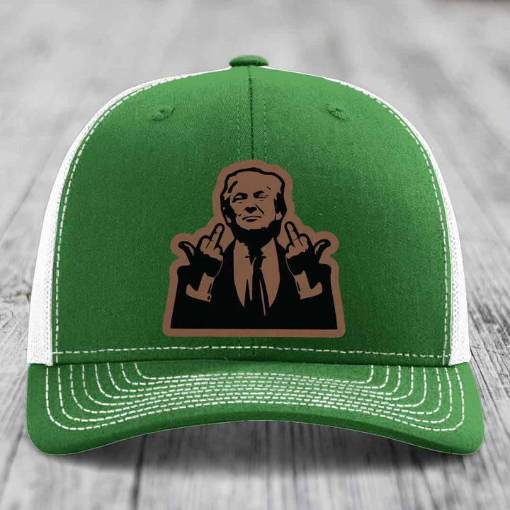 Green trucker hat with white mesh back and stitching, featuring a brown leatherette patch of a man making hand gestures.