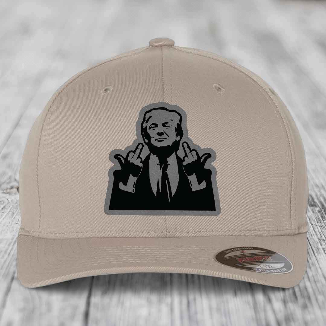 Beige baseball cap with black and grey graphic of man making rude hand gesture, branded Flexfit label visible.
